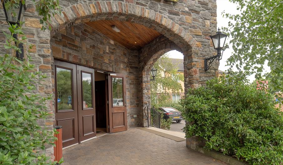 Hotel entrance under stone arches with an exit to a car park.