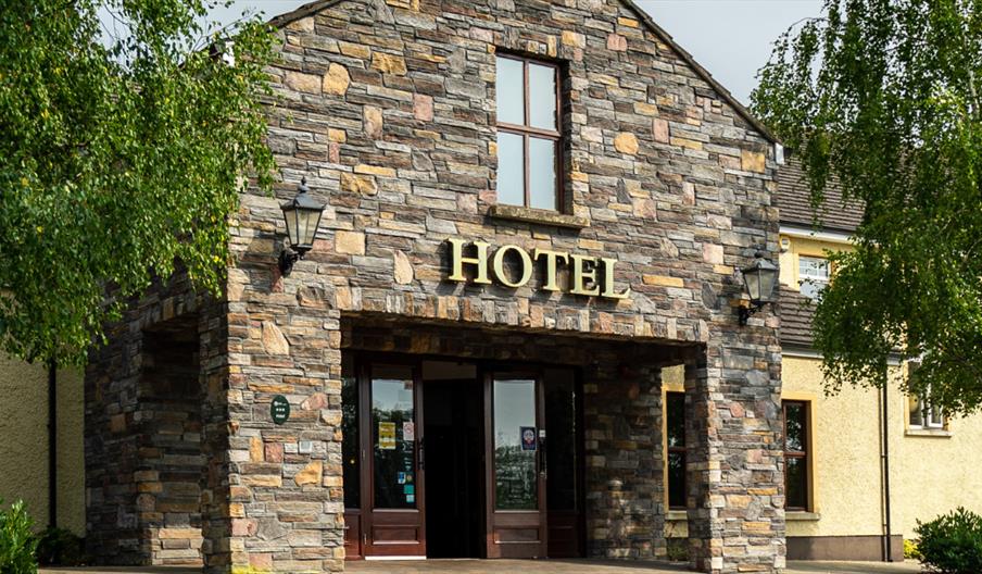 A stone entrance to a hotel with a window and trees.