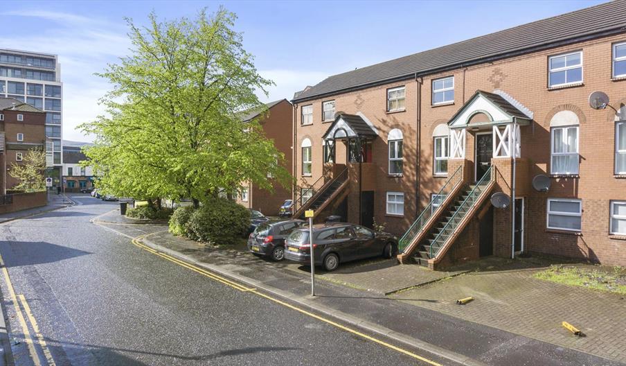 A city apartment complex with outdoor stairs leading to first floor apartments.