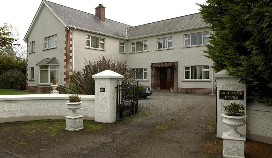 Walled driveway leading to a large guesthouse.