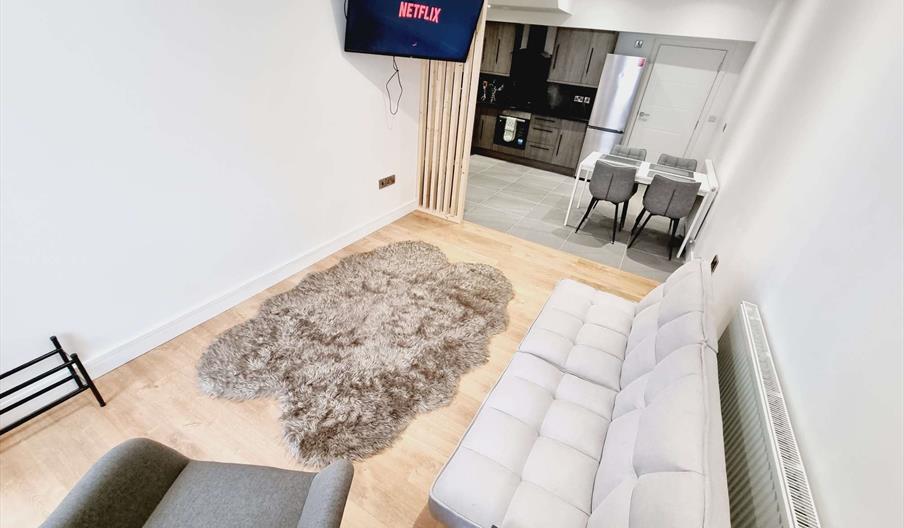 Open floor plan including lounge area with TV and kitchen area.