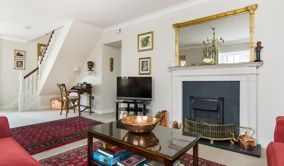 Living room with a coffee table, fireplace, TV, desk and a staircase.