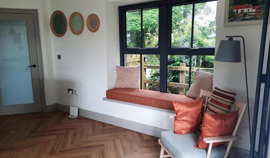 A room with a seat with cushions and a window seat.