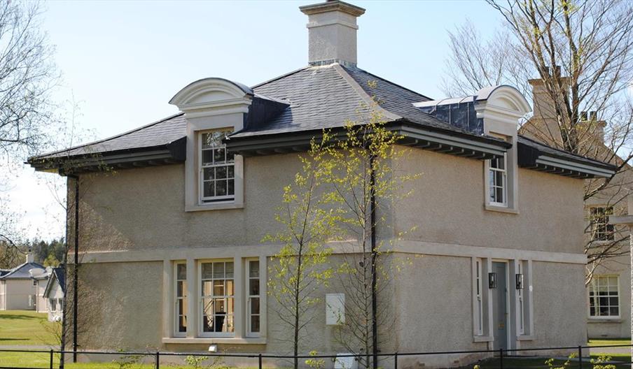 Exterior of two‑storey house with cream exterior, dark roof, and dormer windows