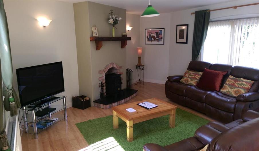 Image shows lounge area with leather sofas, fireplace, coffee table and TV