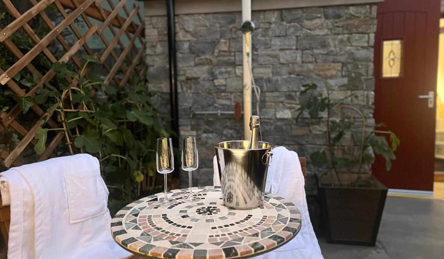 outdoor seating area with two glasses and a bottle of champagne
