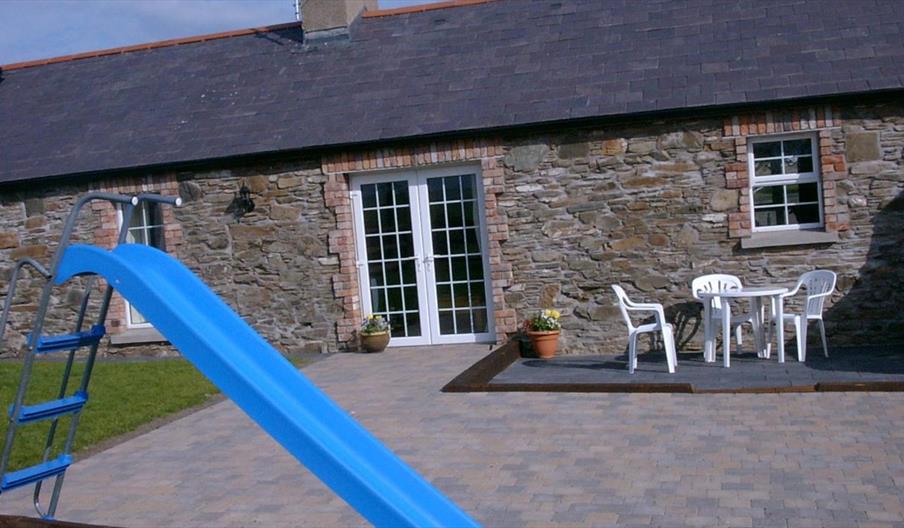 Sally Gardens Cottage backyard with outdoor seating a kids slide