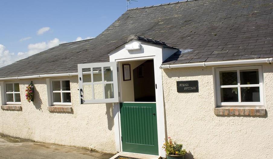 Image shows front of cottage with green stable door as entrance