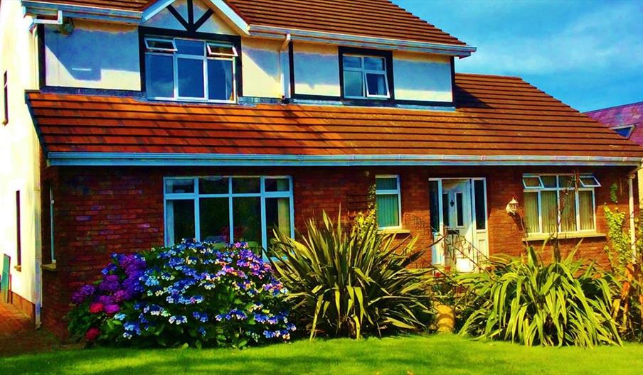 A two-story lodge with a garden of plants and flowers.