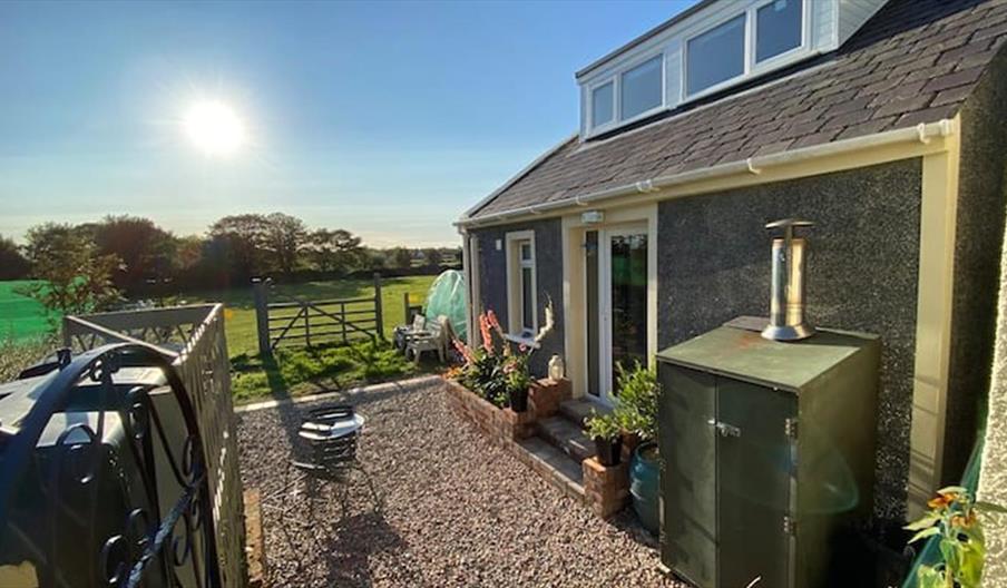 Photo of outside of the accommodation with fields, blue sky and sunshine