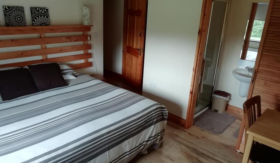 An image of a bedroom in Arley House, large bed with a grey/white striped duvet cover, with ensuite.