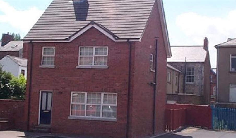 A photo of a dethatched red brick house.