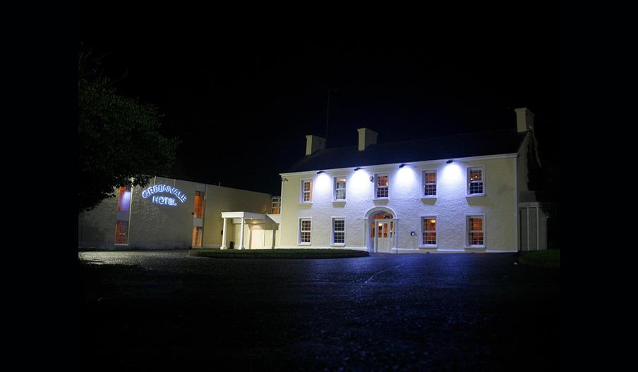 Image of a large two story building lit with four flood lights