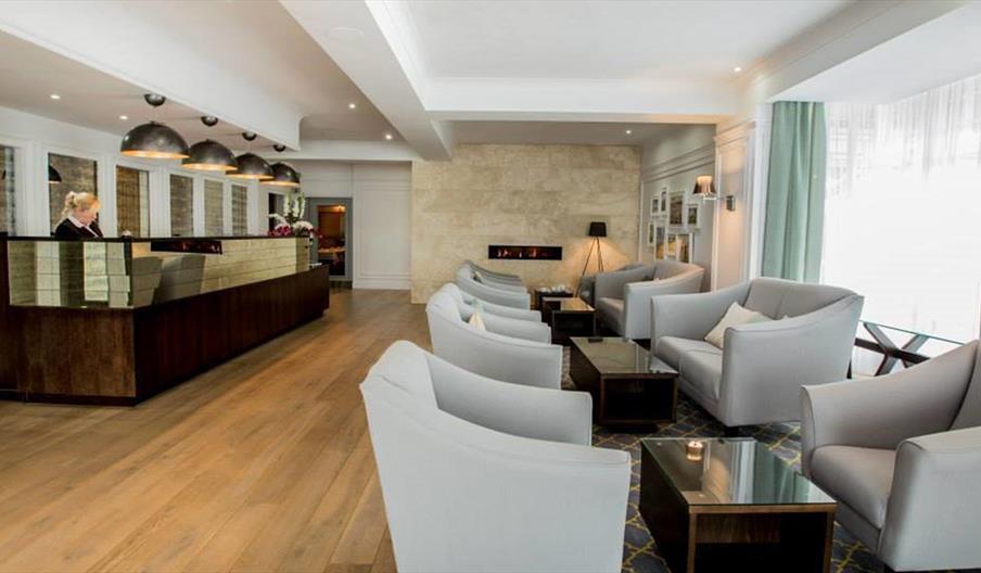 Image shows receptionist at desk in reception area. Also chairs and coffee tables