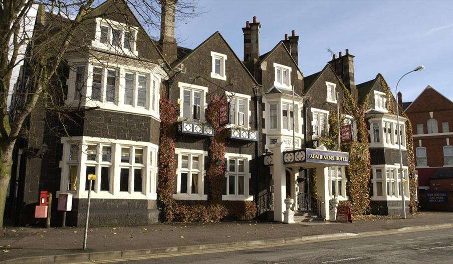 Exterior of hotel with dark brick walls, white trim, and multiple gabled roofs along a street.