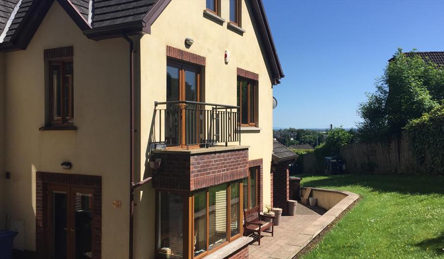 Outside of 2 storey yellow house showing patio doors to small balcony