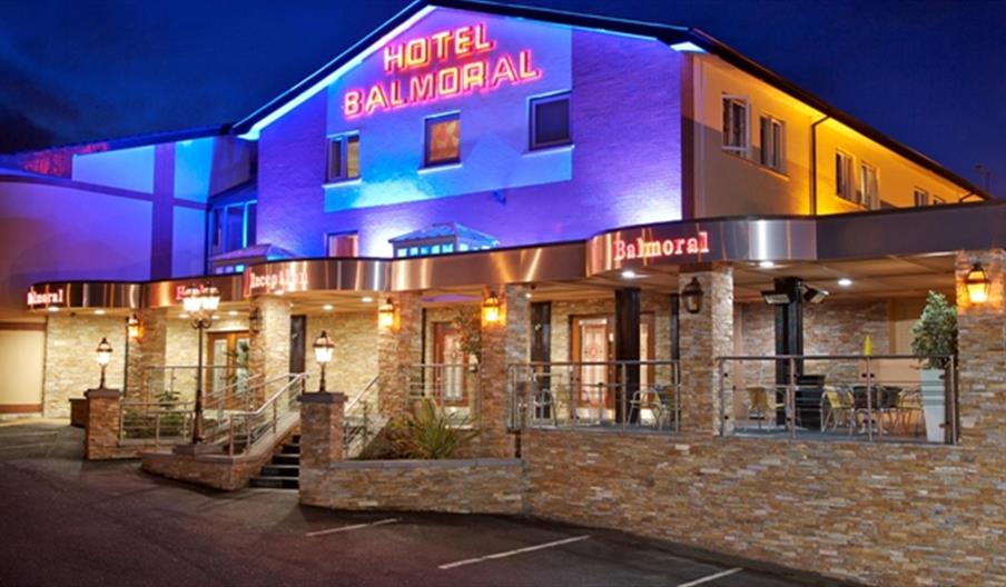 A photo of a hotel with an outdoor seating area lit up at night.