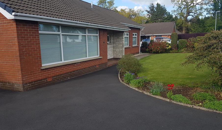 Driveway leading to a bungalow with a well-kept front lawn.