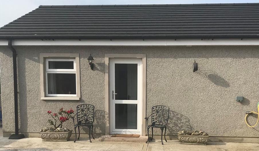 Image is of front of the property with wrought iron chairs at either side of the front door