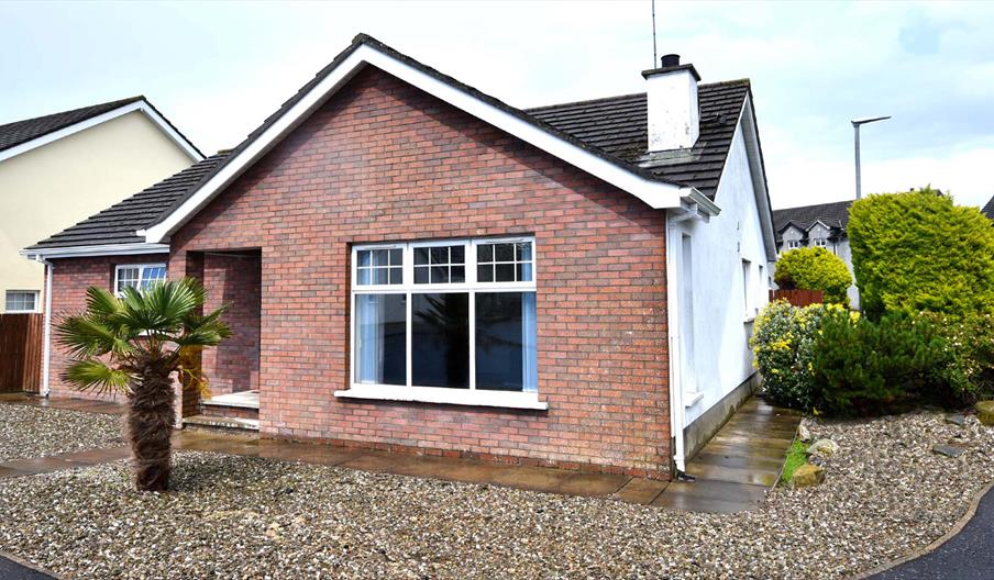 Exterior front and side view of Beachside Bungalow with gravelled drive and garden.