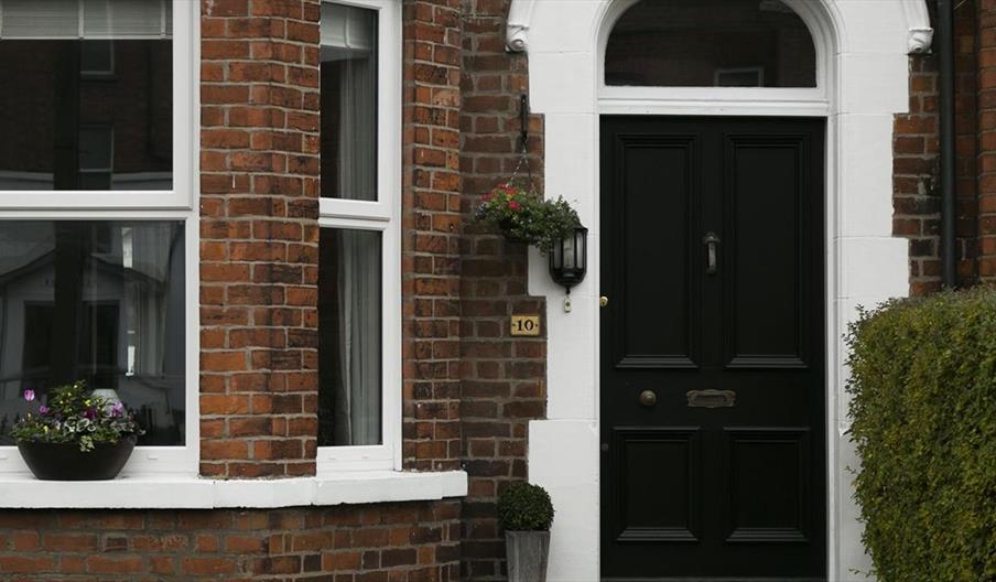 A black front door with a front window decorated with plants.