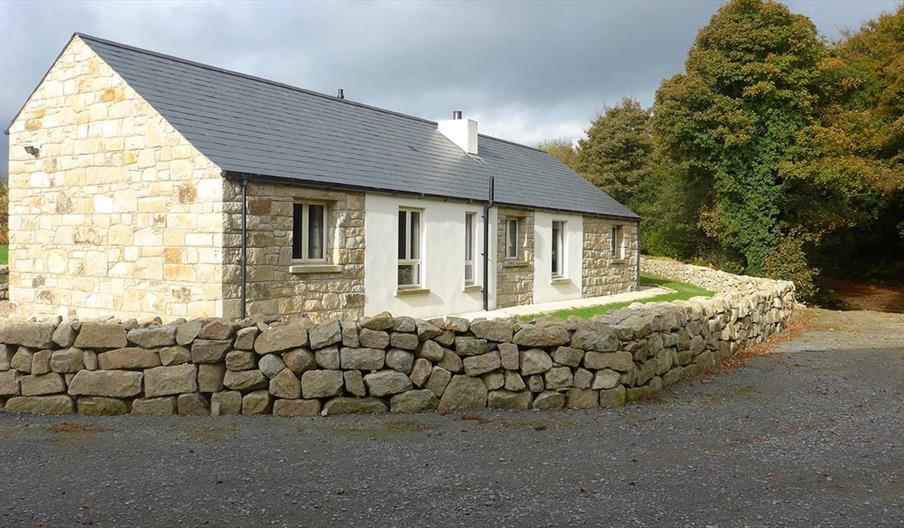 Exterior of Wee Home cottage - Stone cottage with a slate roof, surrounded by a low stone wall in a rural setting.