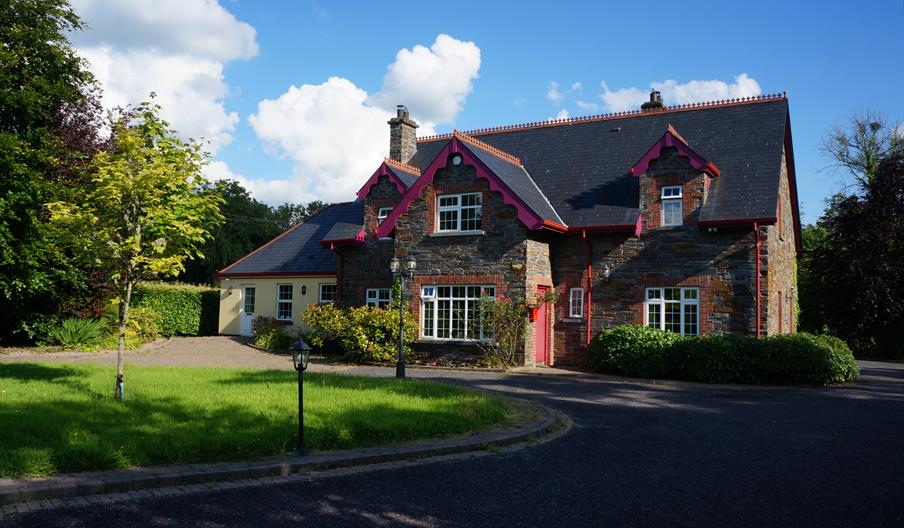 A large lawn area in front of al house in Donegal stone and a smaller painted extension to the left.