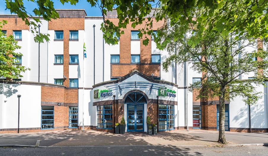 Exterior of the Holiday Inn Express Belfast City, Holiday Inn Express sign on the façade and trees on the sidewalk.