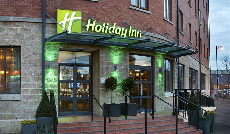 Photo of the entrance of the Holiday Inn Belfast City Centre. Holiday Inn sign above the doors. Stairs and ramp leading to the entrance doors.