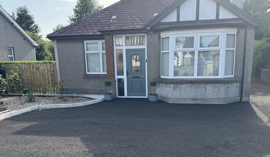 Detached bungalow with red hipped roof and private parking area and garden to front