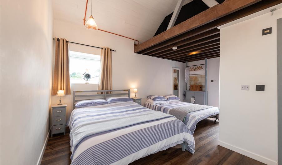 Bedroom with 2 double beds, a window and a small clothes hanger area.