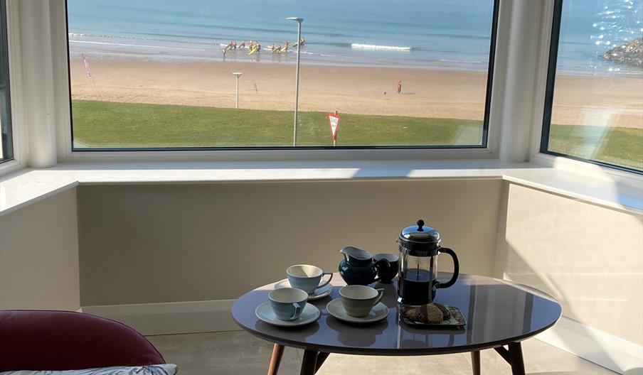 Seating area in front of window overlooking the beach and sea.