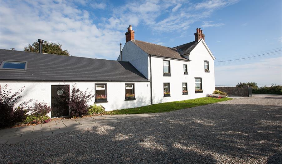 Exterior view of a segmented white house with a large stone driveway.