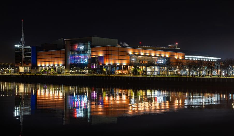 A photograph of The O2 Belfast lit at night.