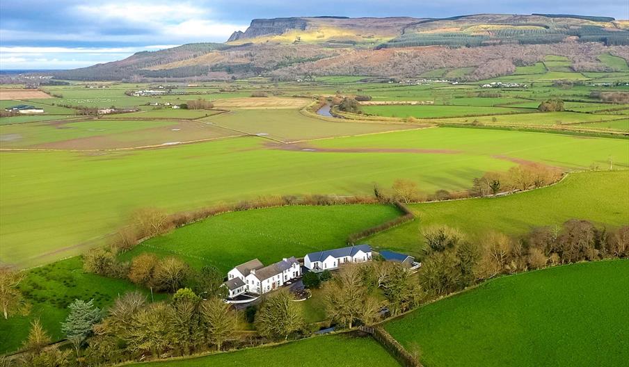 Aerial view of The Willows estate surrounded by green fields at the foot of Binevenagh Mountain near Limavady.