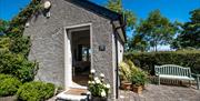 exterior view of Maurice's Stable, paved garden area with summer seat.
