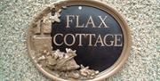 oval sign fixed to outside wall with text, Flax cottage