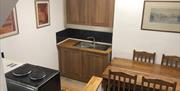 Kitchen dining area with a sink, cooker and wooden dining table.