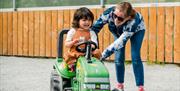 A child happily riding on a ride-on tractor at the ark open farm