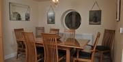 Dining room with a large 8 seated wooden table and a circular window.