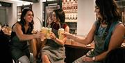 Three women giving a cheers with a cocktail.