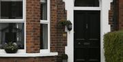 A black front door with a front window decorated with plants.