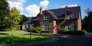 A large lawn area in front of al house in Donegal stone and a smaller painted extension to the left.