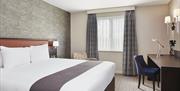 Double bedroom in the Holiday Inn Belfast City Centre. There is a king size bed on the left, desk on the right against the wall and a chair