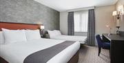 Photo of a family room in Holiday Inn Belfast City Centre. There is a king size bed with a sofa bed set as a bed. There is a desk on the right against