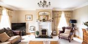Image shows large lounge area with sofa, armchair, fireplace and TV