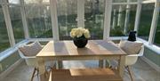 Image shows conservatory area with dining table and chairs