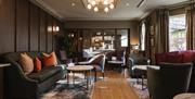 Contemporary hotel lounge with comfortable seating, coffee tables and warm, modern décor.