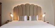 Modern hotel bedroom with a king-size bed, statement headboard and bedside lamps.